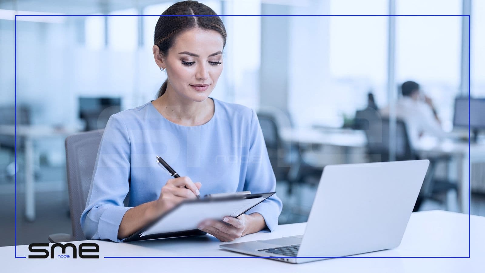 A compliance analyst at a bright office desk ticking through a checklist on a clipboard next to an open laptop, showing the day-to-day job of GRC