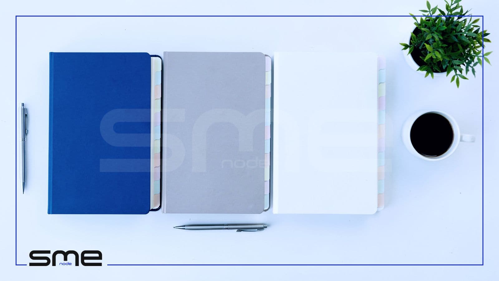 Overhead view of three ring binders in blue, grey and white lined up on a white desk with a pen, coffee and a plant, standing for the three GRC registers
