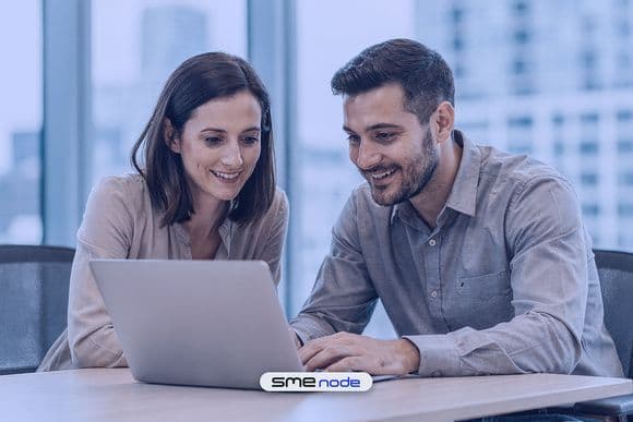 An in-house IT manager and a visiting network engineer working together at one laptop in a bright Toronto office