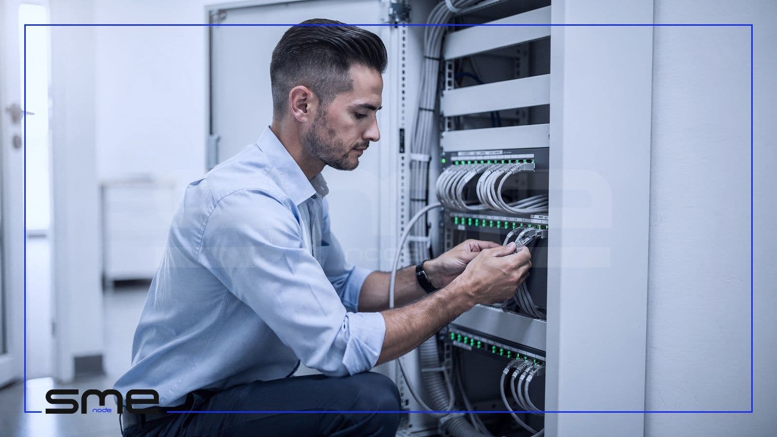 On-site IT engineer connecting patch cables to a network switch in a small office network cabinet