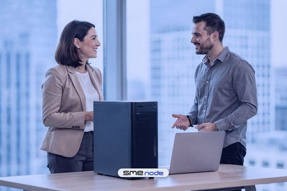 A small business owner and an IT engineer talking beside a tower server and a laptop in a bright Toronto office with a city view