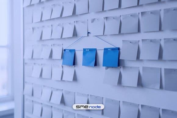 A pin board covered in faded grey blank sticky notes, with three bright blue notes pinned together in the centre to show an AI strategy that picks three use cases out of many
