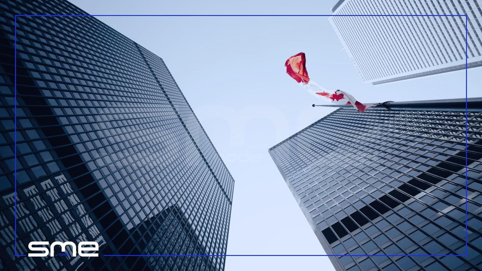 Looking up at dark glass office towers in downtown Toronto with a Canadian flag flying between them, for the Canadian rules a GRC programme has to cover