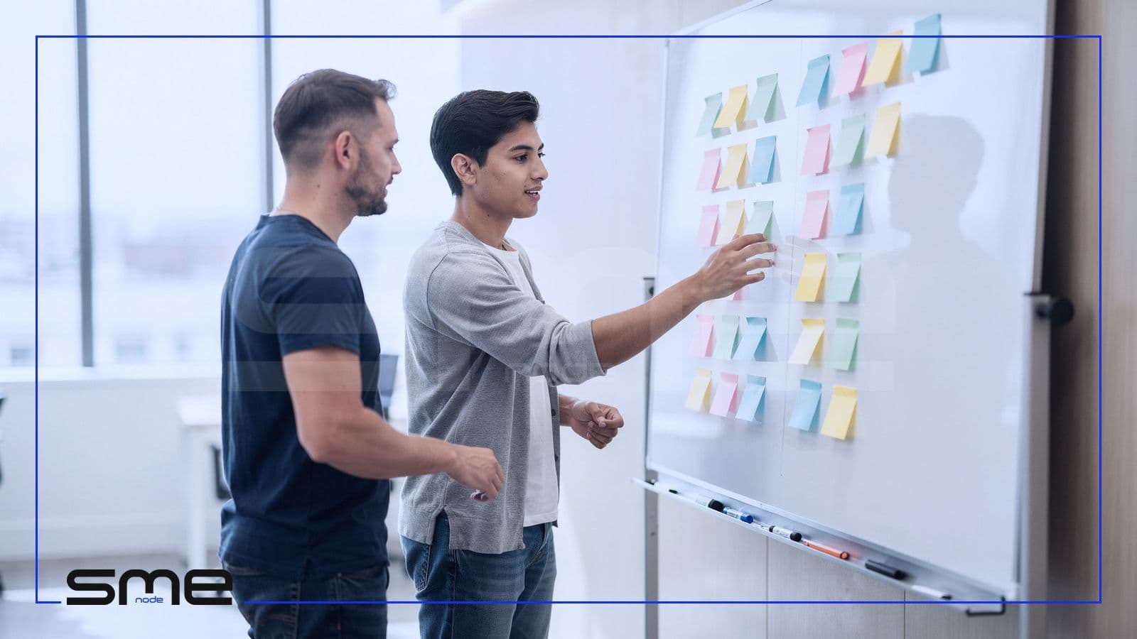 Two IT team members arranging sticky notes on a whiteboard to split responsibilities between in-house staff and a managed IT provider